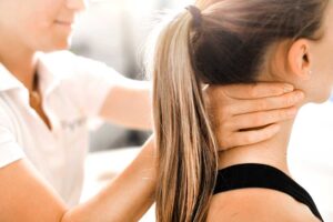 A licensed chiropractor gently performing a spinal adjustment for a middle-aged patient in a clinic setting.