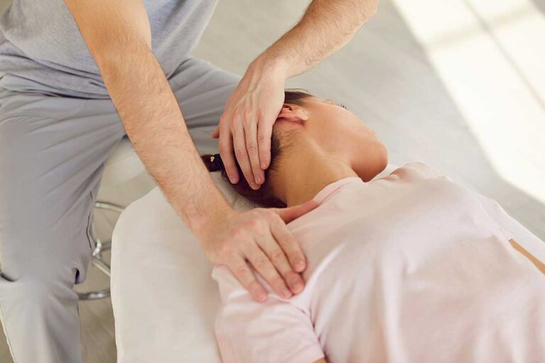 A person at home gently stretching on a living room mat, focusing on lower back and leg muscles.