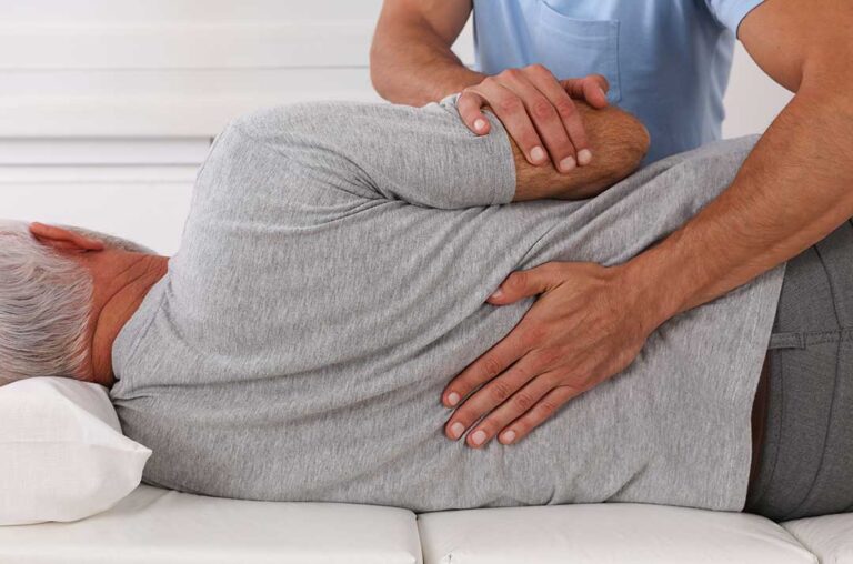 A chiropractor reviews a patient’s health history with them before a gentle physical assessment.